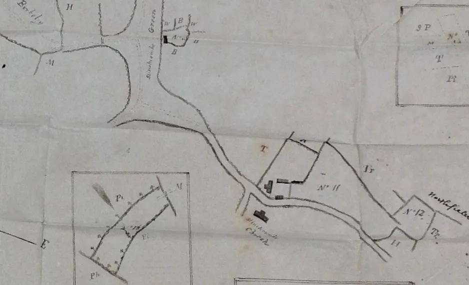 Historical map segment showing a winding river, roads, and labeled plots with small building icons used for navigation or land use.
