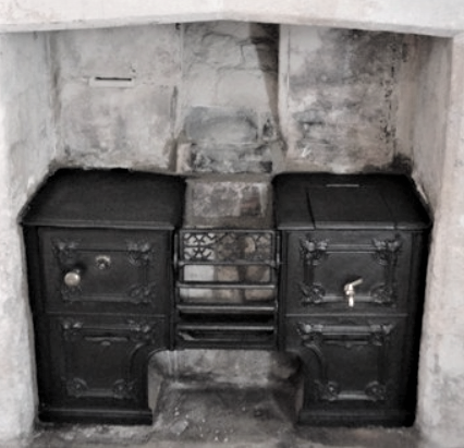 Two black cast-iron stoves with a small central oven built into a stone alcove.