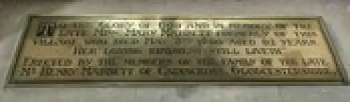 Bronze commemorative plaque embedded in a marble floor with a long engraved dedication text.