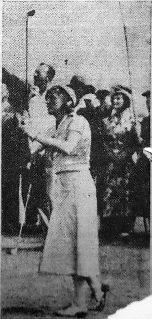 A person in a light-colored suit walking with a cane on a street, surrounded by a crowd in the background (black-and-white vintage photo).